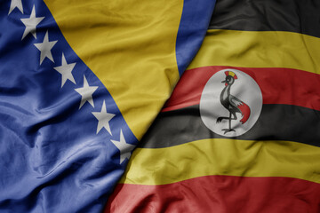 big waving national colorful flag of uganda and national flag of bosnia and herzegovina.