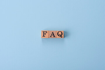 The inscription FAQ made up of wooden cubes on a plain background