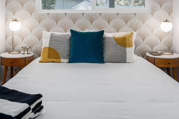 Modern guest bedroom with comfortable bed, pillows, nightstands, and scale mosaic tile wallpaper