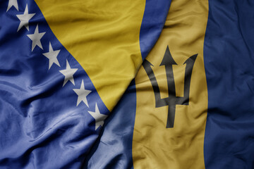 big waving national colorful flag of barbados and national flag of bosnia and herzegovina.