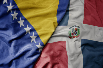 big waving national colorful flag of dominican republic and national flag of bosnia and herzegovina.