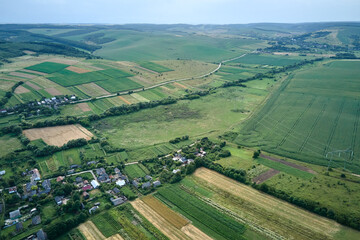 Aerial landscape view of village houses and distant green cultivated agricultural fields with...