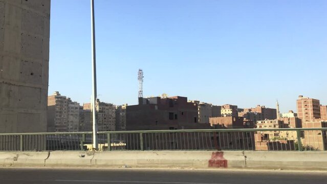 May 24, 2021 - Cairo, Egypt. Half built buildings in bright sun with little foliage or shade plants line the landscape between the airport and Giza.