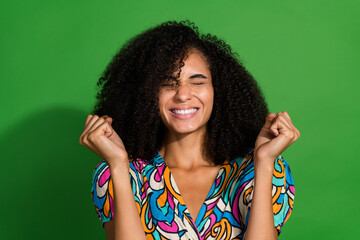 Portrait of young delightful lady with chevelure clenched teeth closed eyes raised fists up want to...