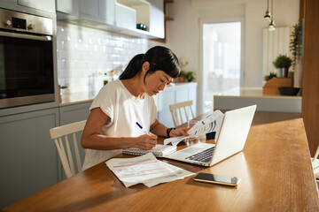 Woman doing bills with laptop at home