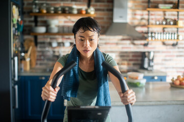 Young Asian woman on a exercise bike at home