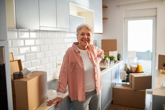 Smiling portrait of a senior woman at home with moving boxes around