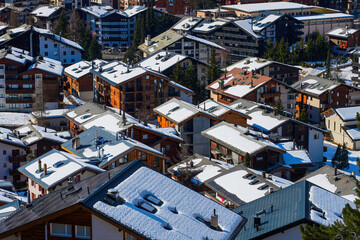 Snow-covered rooftops of Zermatt in the Swiss Alps in winter - Idyllic landscape with wooden...