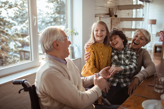Grandparents and grandchildren laughing together indoors during winter