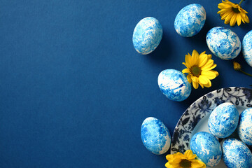 Happy Easter greeting card. Marble blue Easter eggs with yellow flowers on dark blue background.