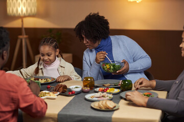 Portrait of mother talking to young girl using smartphone at dinner table and watching videos online