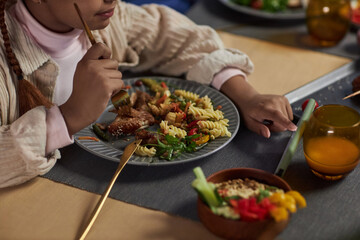 Closeup of young girl using smartphone while eating at dinner table and tapping screen copy space 