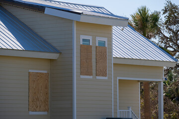 Plywood mounted as storm shutters for hurricane protection of house windows. Protective measures...