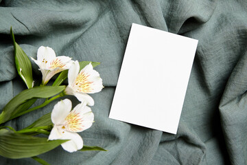 Single blank card mockup with white alstroemeria flowers on fabric