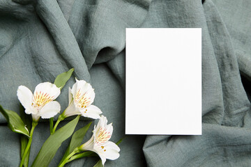 Single blank card mockup with white alstroemeria flowers on fabric