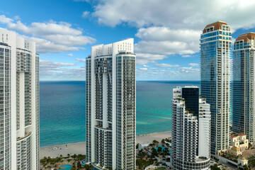 View from above of luxurious highrise hotels and condos on Atlantic ocean shore in Sunny Isles Beach city. American tourism infrastructure in southern Florida - obrazy, fototapety, plakaty