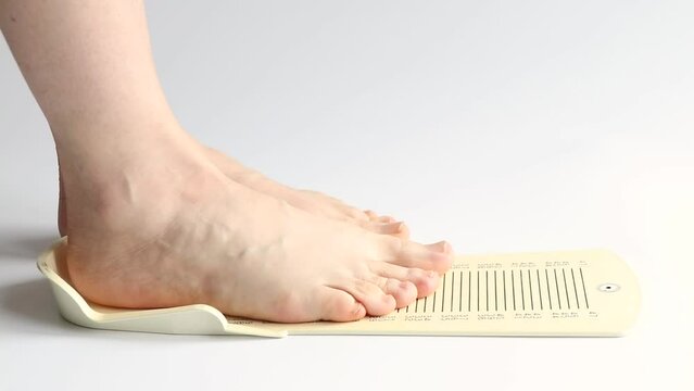 A woman's foot is measured on a measuring board to determine the shoe size, measuring the foot size