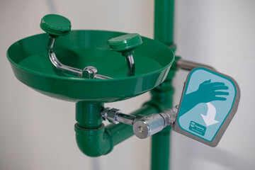 Green emergency eyewash station with a push lever, designed for industrial safety and rapid eye...