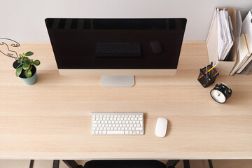 Blank computer monitor with alarm clock on table in office, top view