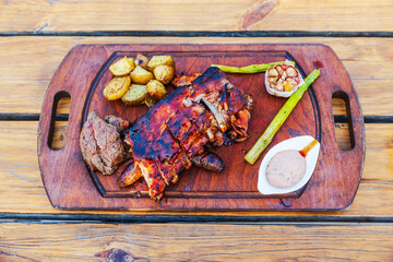 Close-up view of grilled dinner on wooden platter resting atop table in al fresco restaurant setting. Curacao.