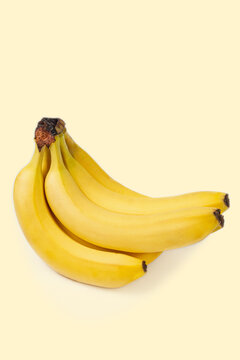 A bunch of bananas on a beige cream color background. Isolated with clipping masks. Beautiful yellow fruits. Conceptual photo. Vertical image.