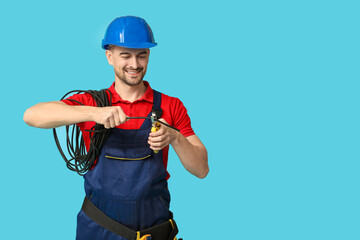 Portrait of male electrician with pliers and wires on blue background