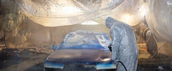 painting a car in the garage with a spray gun blue. Do-it-yourself car painting and varnishing.