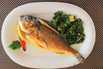 Fried fish with herbs on plate. Fresh Seafood in restaurant, cafe, hotel. Fish dish