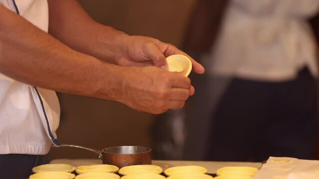 The making of traditional Portugese egg custard tarts called pasteis de nata in portugese language. Close up 4K video with a pastry cheef creating the shapes of these delicious cakes from Portugal.