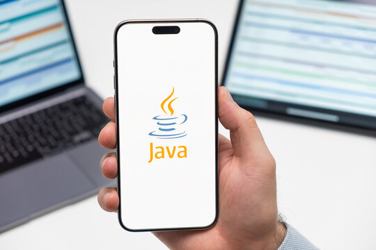PRAGUE, CZECH REPUBLIC - JANUARY 21 2024: Java logo on the screen of smartphone in mans hand on the workplace background. 