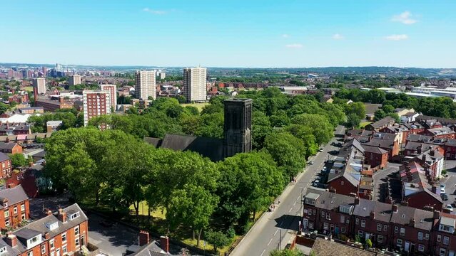 Aerial footage of the town of Armley in Leeds West Yorkshire UK, showing rows of houses and a historical Church and grounds from above in the summer time