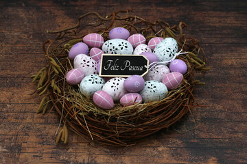 Cesta decorativa de Pascua con huevos de Pascua, flores y el saludo “Felices Pascuas”.