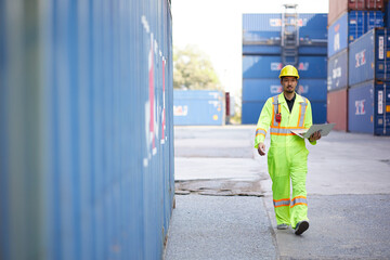 worker or engineer holding laptop computer and looking at containers warehouse storage