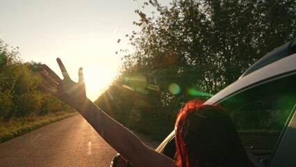 Road trip happy redhead woman with raising hand enjoy freedom fresh air bright sun riding car...