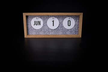 A wooden calendar block showing the date June 10th on a dark black background, save the date or date of event concept