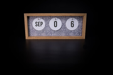 A wooden calendar block showing the date September 6th on a dark black background, save the date or date of event concept