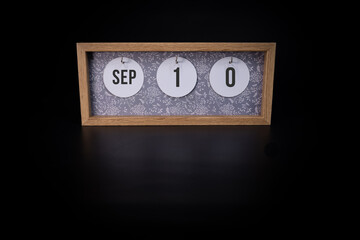 A wooden calendar block showing the date September 10th on a dark black background, save the date or date of event concept