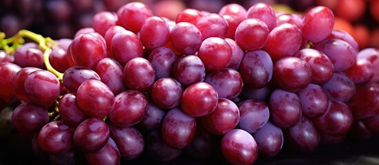 A cluster of delicious red globe grapes sits on top of a wooden table, showcasing a variety of sweetness ready for global export.