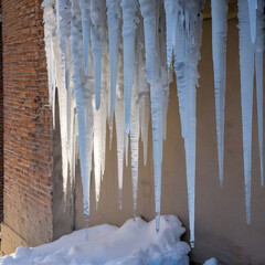Huge icicles hang from the wall of the building. Generative AI