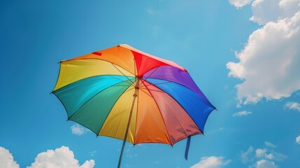 Fototapeta na wymiar Rainbow umbrella on blue sky background