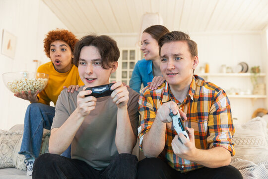 Home party. Cheerful group of friends playing video games at home. Happy diverse group buddies having fun together indoor. Friendship leisure entertainment concept. Young best friends enjoying weekend