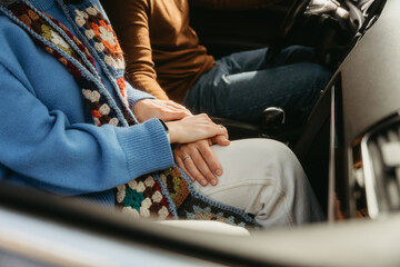 Couple in car holding hands, finding comfort in each other