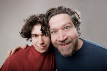 funny portrait of father and teenage son looking at camera