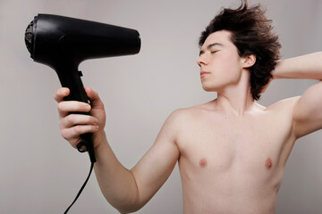 young boy drying his hair with a hairdryer