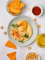 Plate with hummus, chips, olive oil, paprika, herbs. Traditional oriental snack. View from above.