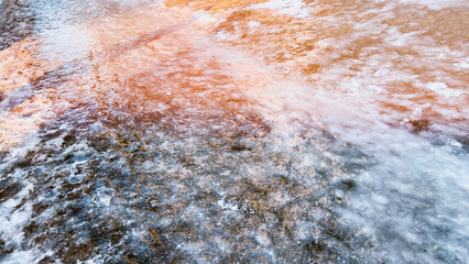 Frozen puddles outdoors. Spring landscape. Slippery road background. Film grain texture. Soft focus. Blur