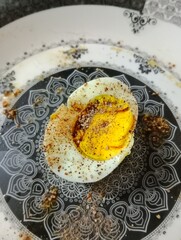 A perfectly boiled egg sprinkled with freshly ground pepper, showcasing a simple yet delicious breakfast or snack option.