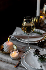 Elegant decor for Christmas family dinner. Center piece with burning candles, vintage chandelier. Zero waste eco-friendly reusable home decoration, fir tree branches. Cozy atmosphere, wooden furniture