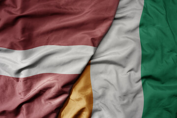 big waving national colorful flag of cote divoire and national flag of latvia.