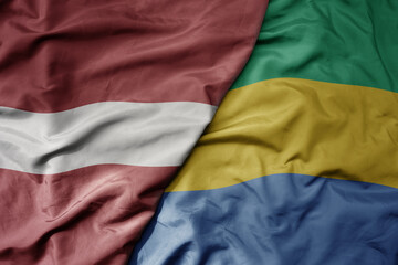 big waving national colorful flag of gabon and national flag of latvia.